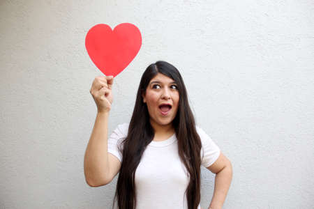 Latin adult woman shows her enthusiasm for the arrival of February and celebrate Valentine's Day of Love and Friendship with love and affection by givingの写真素材