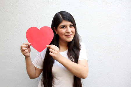 Latin adult woman shows her enthusiasm for the arrival of February and celebrate Valentine's Day of Love and Friendship with love and affection by givingの写真素材