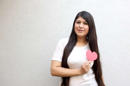 Latin adult woman shows her enthusiasm for the arrival of February and celebrate Valentine's Day of Love and Friendship with love and affection by givingの写真素材