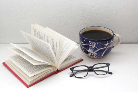 Reading time with an open book ready to be read in the solitude of a room with glasses and coffee to show tranquility and relaxationの写真素材