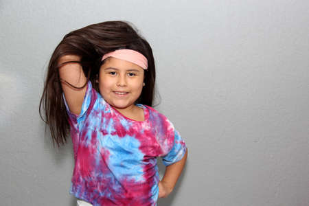 10 year old Hispanic girl with very long black straight hair modeling happily for the camera in a tie dye style shirtの写真素材