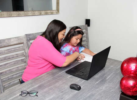Hispanic Mom and Daughter Home School with Homework in New Normal Due to Covid-19 Pandemicの写真素材