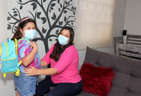 Latina mom and daughter prepare for back to school with backpack and mask in the new normal after the quarantine by the Covid-19 pandemicの写真素材