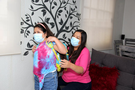 Latina mom and daughter prepare for back to school with backpack and mask in the new normal after the quarantine by the Covid-19 pandemicの写真素材