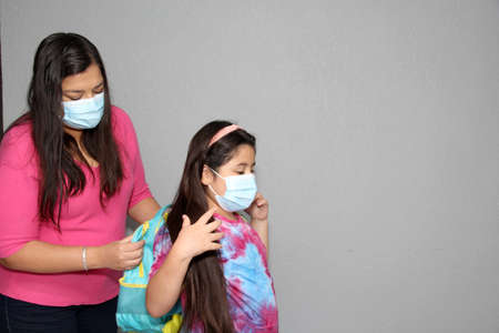 Latina mom and daughter prepare for back to school in the new normal due to the Covid-19 pandemic with backpack and face shield to protect from Coronavirusの写真素材