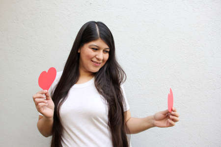 Latin adult woman with a big red heart shows her enthusiasm for the arrival of February and celebrate Valentine's Day of Love and Friendship with her family, partner and friends with joy and affectionの写真素材