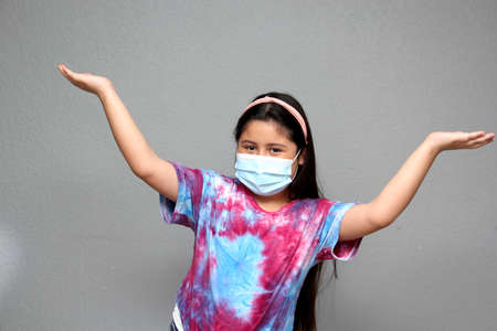 Happy Latin Little Girl Wearing Face Masks To Protect Herself From Coronavirus In The New Normal Due To The Covid-19 Pandemicの写真素材