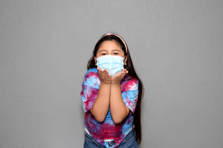 Happy Latin Little Girl Wearing Face Masks To Protect Herself From Coronavirus In The New Normal Due To The Covid-19 Pandemicの写真素材