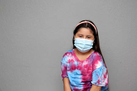 Happy Latin Little Girl Wearing Face Masks To Protect Herself From Coronavirus In The New Normal Due To The Covid-19 Pandemicの写真素材