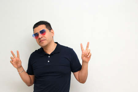 Latin adult man with a heart-shaped sunglasses shows his enthusiasm for the arrival of February and celebrate the Day of Love and Friendship with his partner, friends and family sharing affectionの写真素材