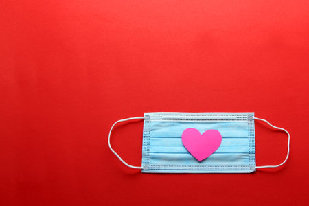 Tri-layer protective mask for clinical use with white hearts on a red backgroundの写真素材