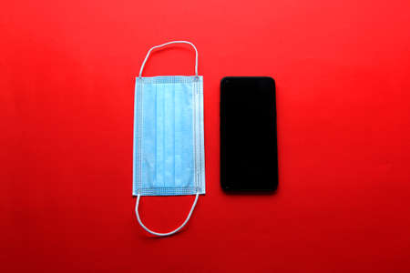 Valentine's Day in pandemic by covid-19, mobile phone with protection mask clinical use and pink heartsの写真素材