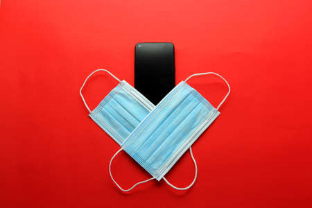Valentine's Day in pandemic by covid-19, mobile phone with protection mask clinical use and pink heartsの写真素材