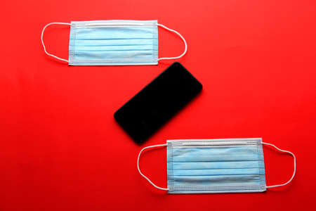 Valentine's Day in pandemic by covid-19, mobile phone with protection mask clinical use and pink heartsの写真素材