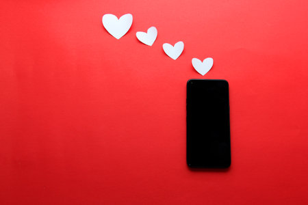 Valentine's Day in pandemic by covid-19, mobile phone with protection mask clinical use and pink heartsの写真素材