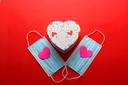 Valentine's Day in pendemic for covid-19, teddy bear, box of chocolates, flowers and hearts with protection mask clinical useの写真素材
