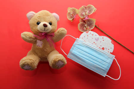 Valentine's Day in pendemic for covid-19, teddy bear, box of chocolates, flowers and hearts with protection mask clinical useの写真素材