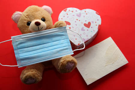 Valentine's Day in pendemic for covid-19, teddy bear, box of chocolates, flowers and hearts with protection mask clinical useの写真素材