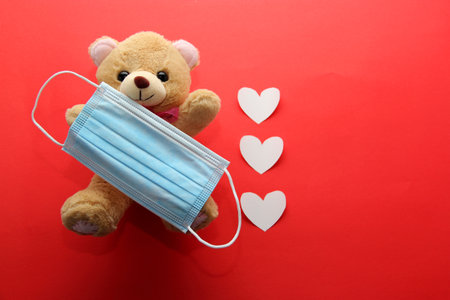 Valentine's Day in pendemic for covid-19, teddy bear, box of chocolates, flowers and hearts with protection mask clinical useの写真素材