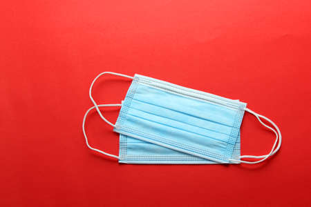 Three-layer heat-sealed protection mask for clinical use for covid-19 pandemic on red backgroundの写真素材