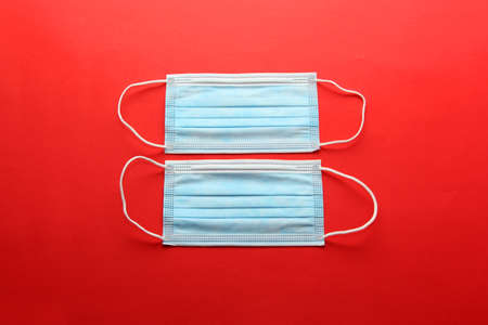 Three-layer heat-sealed protection mask for clinical use for covid-19 pandemic on red backgroundの写真素材