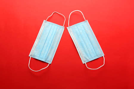 Three-layer heat-sealed protection mask for clinical use for covid-19 pandemic on red backgroundの写真素材