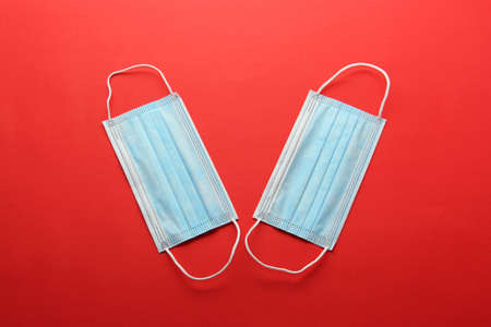 Three-layer heat-sealed protection mask for clinical use for covid-19 pandemic on red backgroundの写真素材