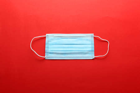 Three-layer heat-sealed protection mask for clinical use for covid-19 pandemic on red backgroundの写真素材