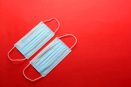 Three-layer heat-sealed protection mask for clinical use for covid-19 pandemic on red backgroundの写真素材