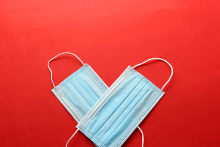 Three-layer heat-sealed protection mask for clinical use for covid-19 pandemic on red backgroundの写真素材