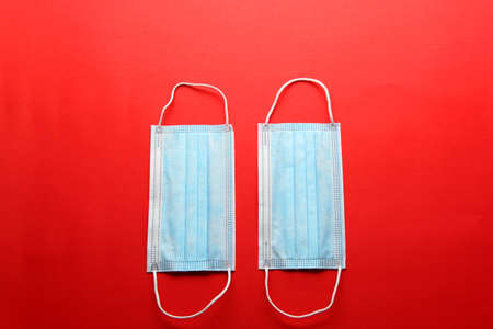 Three-layer heat-sealed protection mask for clinical use for covid-19 pandemic on red backgroundの写真素材
