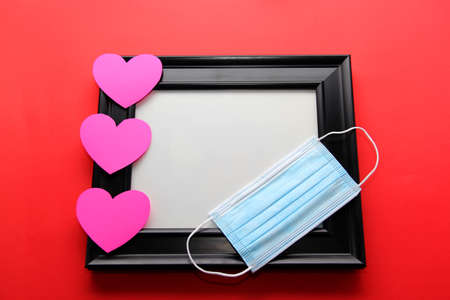 Valentine's Day gifts in pandemic by covid-19, picture holder and flowers with protection mask for clinical use and pink heartsの写真素材