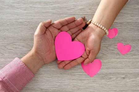 Valentine's Day. heart in female and male couple hands vintage wooden background for advertising...