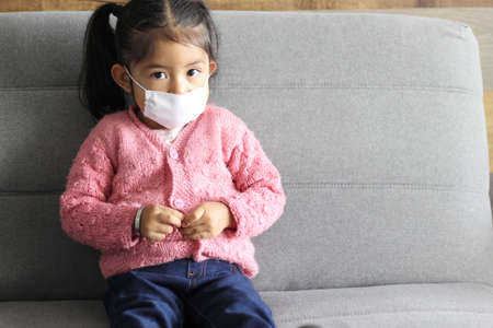 2 year old girl with protective face mask for new normal of covid-19 with colorful wall and background texturesの写真素材
