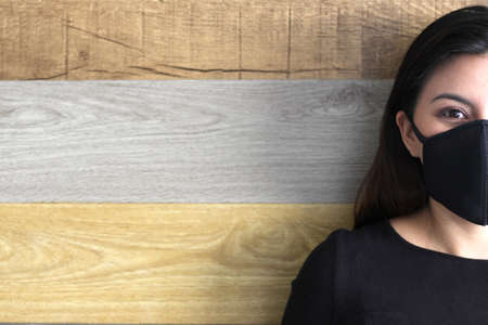 latin woman with black protective mask and colorful wall in the background, new normal covid-19の写真素材