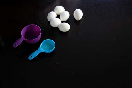 kitchen utensils for measuring and eggs on black table background