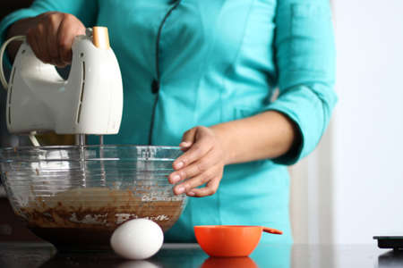 latin woman chef preparing whipping flour for cake with kitchen utensils