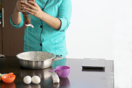 latin woman chef preparing whipping flour for cake with kitchen utensilsの写真素材