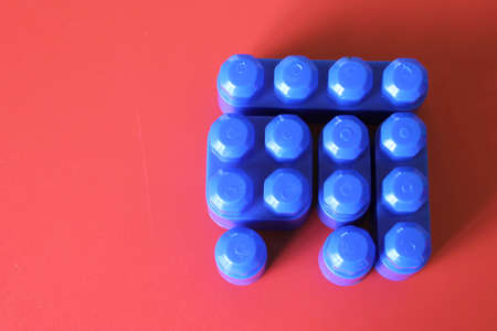 Buildable colored plastic blocks to play, build and organize on a red background as a concept of...