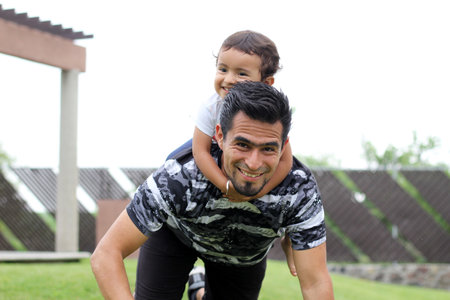 Latino dad with 3-year-old girl playing on the park lawnの写真素材