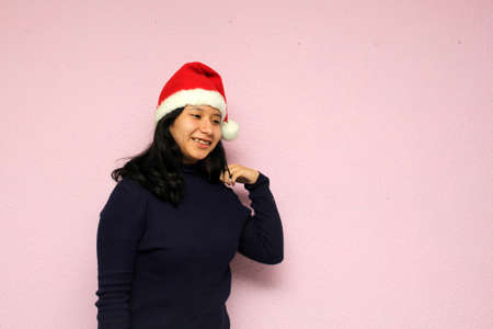 Young teenager woman with santa hat shows her enthusiasm for the arrival of december and celebrate christmasの写真素材