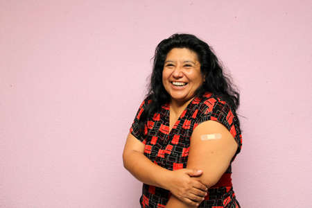 Body positive overweight adult laina woman shows her arm recently vaccinated against Covid-19 in the new normal for the Coronavirus pandemicの写真素材