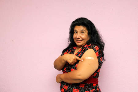 Body positive overweight adult laina woman shows her arm recently vaccinated against Covid-19 in the new normal for the Coronavirus pandemicの写真素材