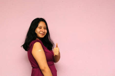 Young Latina teenager shows her arm recently vaccinated against Covid-19 in the new normal for the Coronavirus pandemicの写真素材
