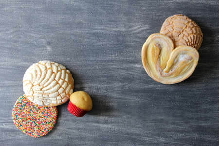 Mexican sweet bread on vintage gray table.Shell, cupcake, bow tie, ear, biscuit with multicolored twigsの写真素材