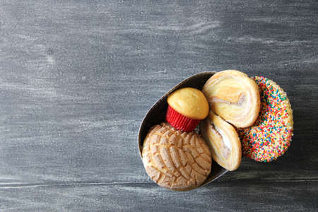 Mexican sweet bread on vintage gray table.Shell, cupcake, bow tie, ear, biscuit with multicolored twigsの写真素材