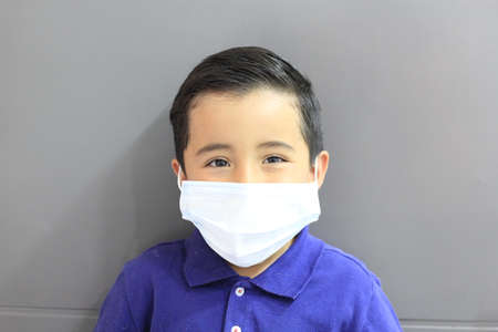 Latino boy 6 years old with blue t-shirt and protection mask due to covid pandemic