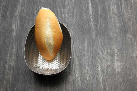 Fresh, delicious, fluffy, hot, freshly made Mexican bolillo bread, white bread, loaf, French bread made from wheat flour ready to eat in a basket on gray wooden tableの写真素材