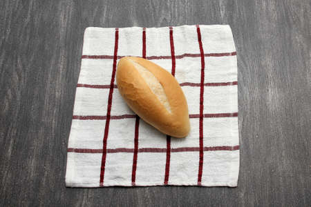 Fresh, delicious, fluffy, crispy, hot, freshly made Mexican bolillo bread, white bread, loaf, or French bread on a napkin on a gray wooden table ready to eatの写真素材