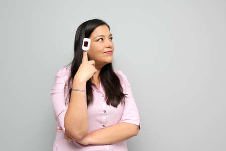 Latin adult woman with dark brown hair shows in her hand an oximeter on her finger that measures her oxygenation for suspicion of Covid-19 in the new normality due to the coronavirus pandemicの写真素材
